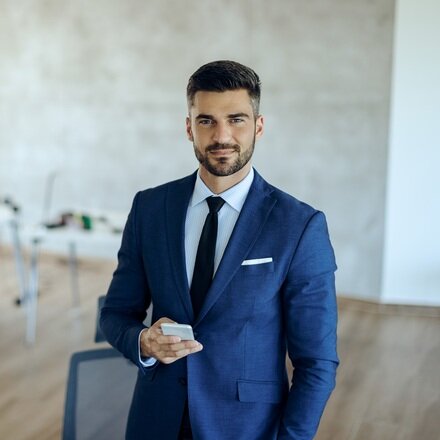 young-businessman-using-mobile-phone-office-looking-camera_s.jpg